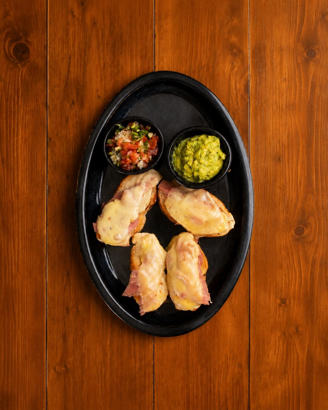 Molletes de jamón con queso gratinado, guacamole y pico de gallo