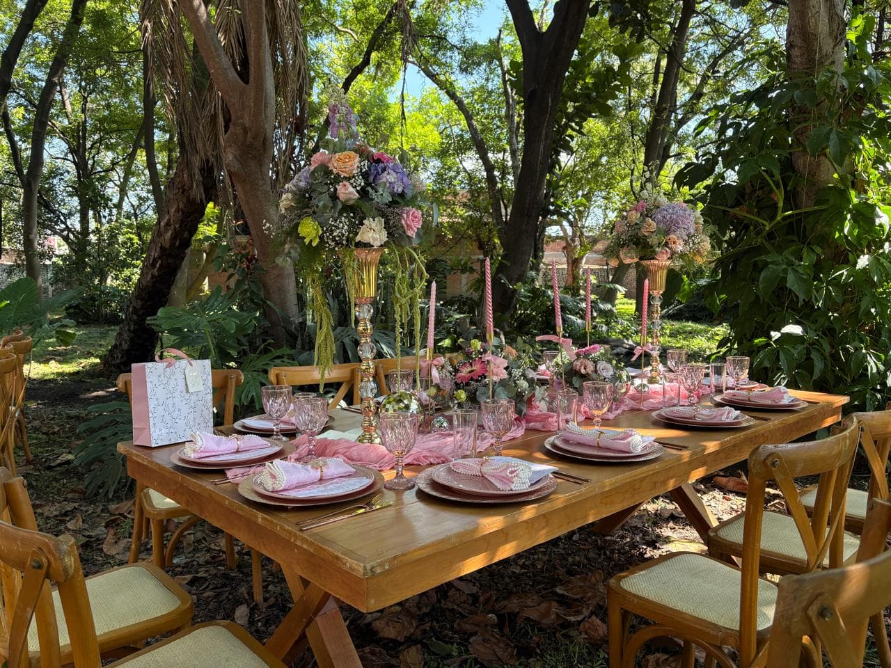 Mesa para evento montada por Shukran en un jardín con flores y vajilla rosa
